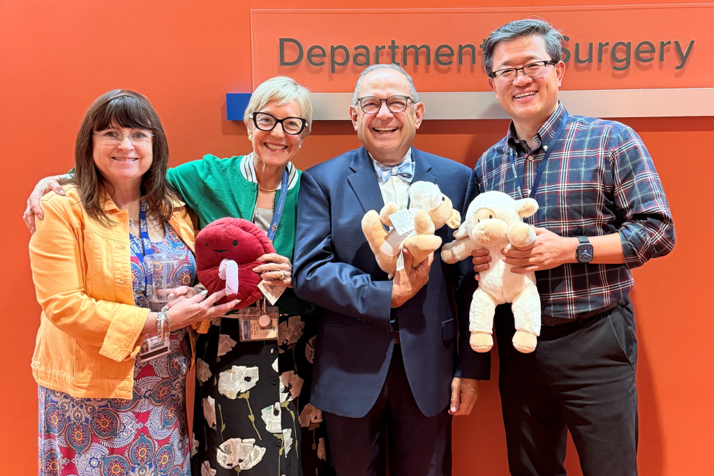 Four people stand against an orange background. They are holding stuffed sheep and blood cells.